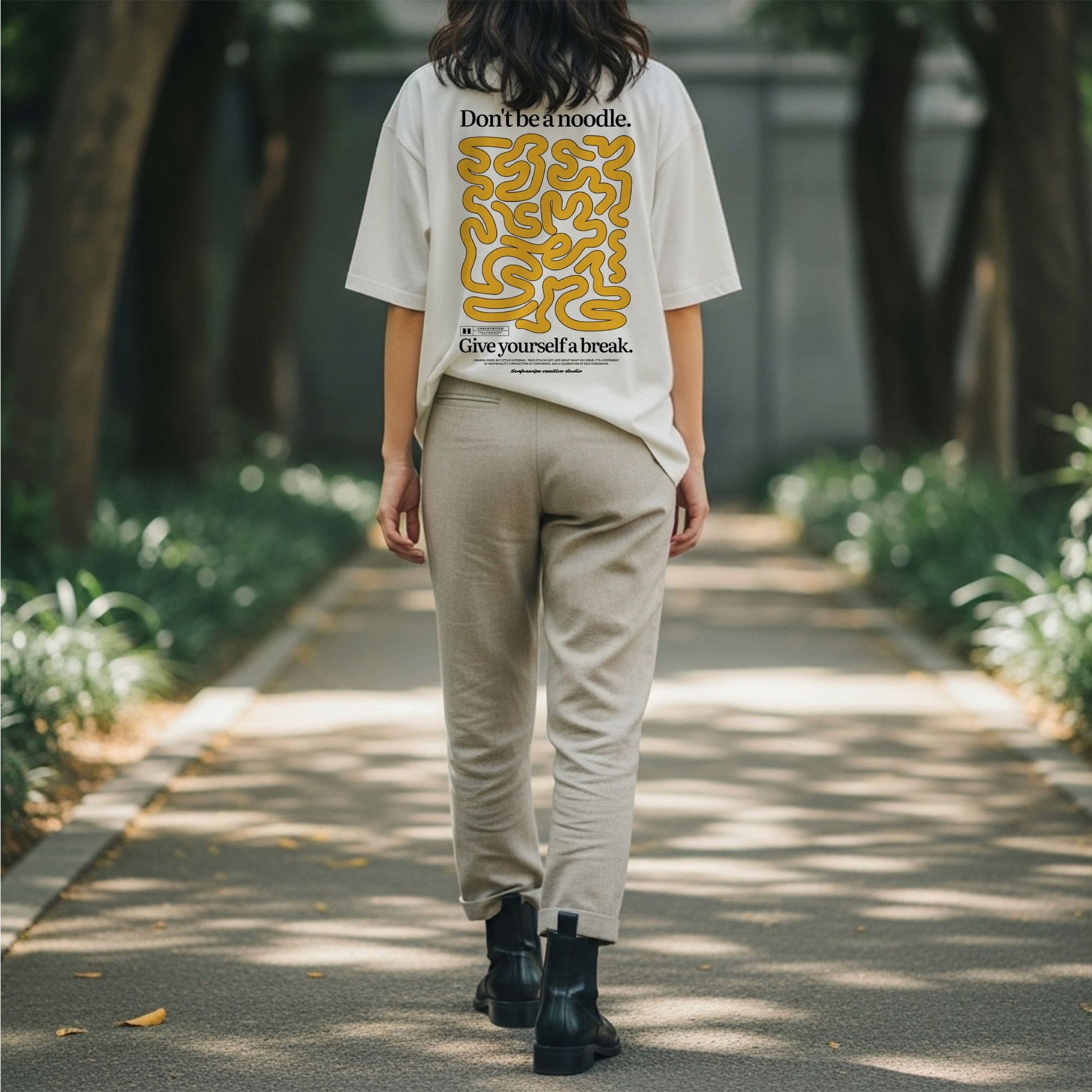 Person walking on a path wearing a white t-shirt with yellow text and graphics.