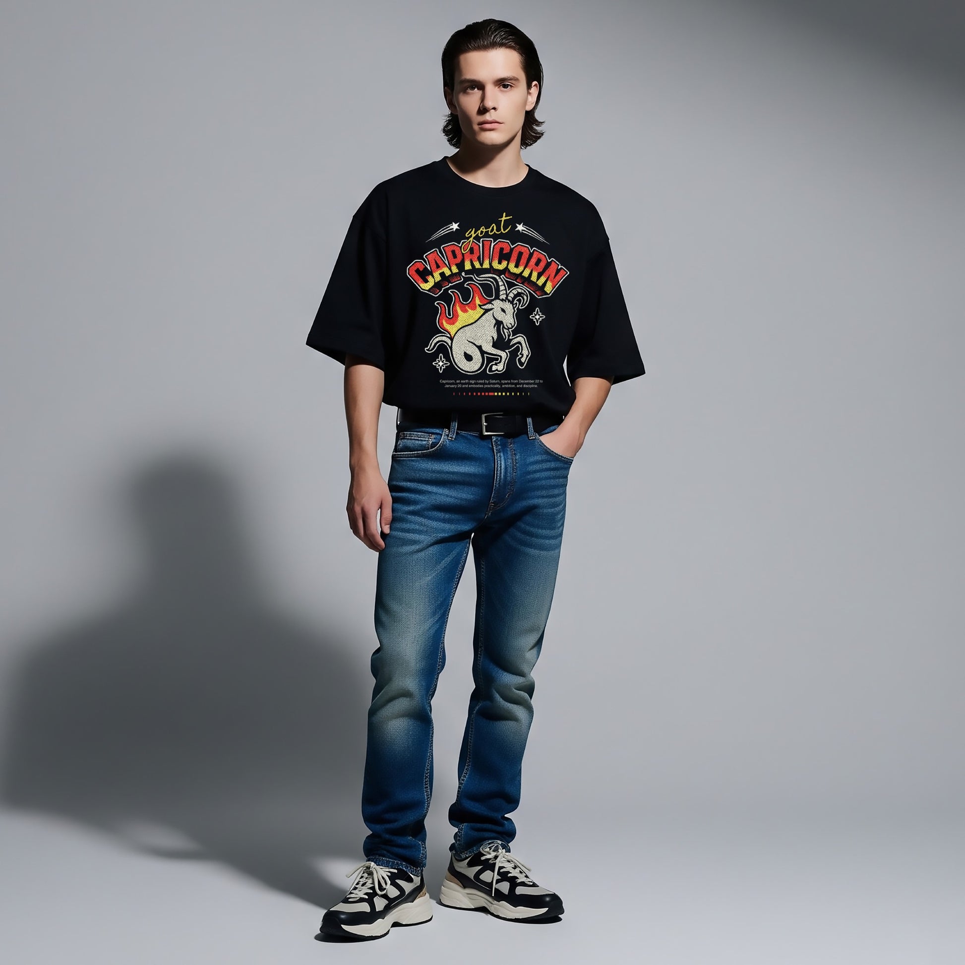 Person wearing a black t-shirt with a graphic design and blue jeans on a gray background