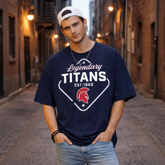 Man wearing a navy blue 'Legendary Titans' t-shirt in an urban alleyway.