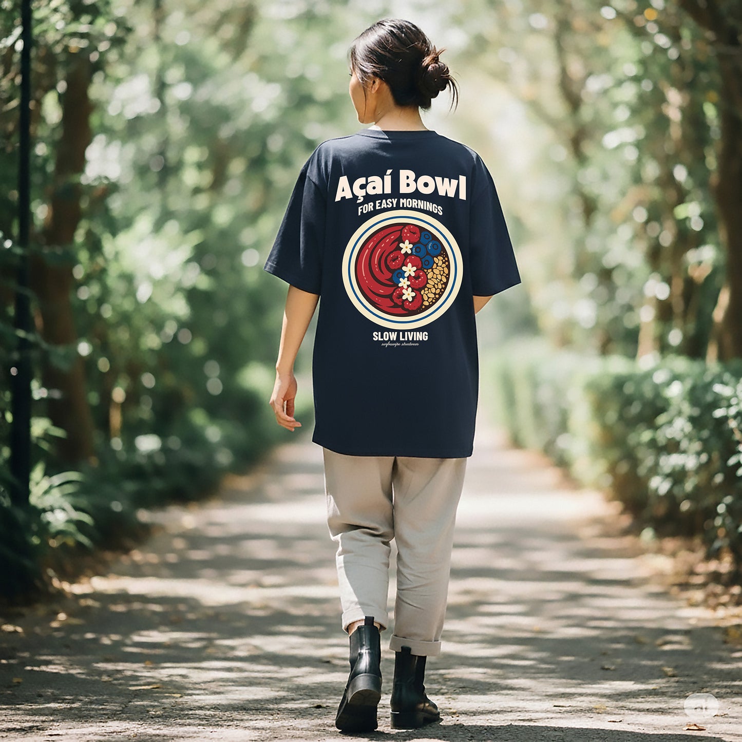 Person wearing a navy blue t-shirt with a colorful graphic and text, walking through a forest.