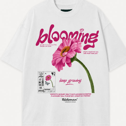White t-shirt with pink flower graphic and 'blooming' text on a white background