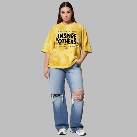 Person wearing a yellow t-shirt with text and ripped jeans on a gray background