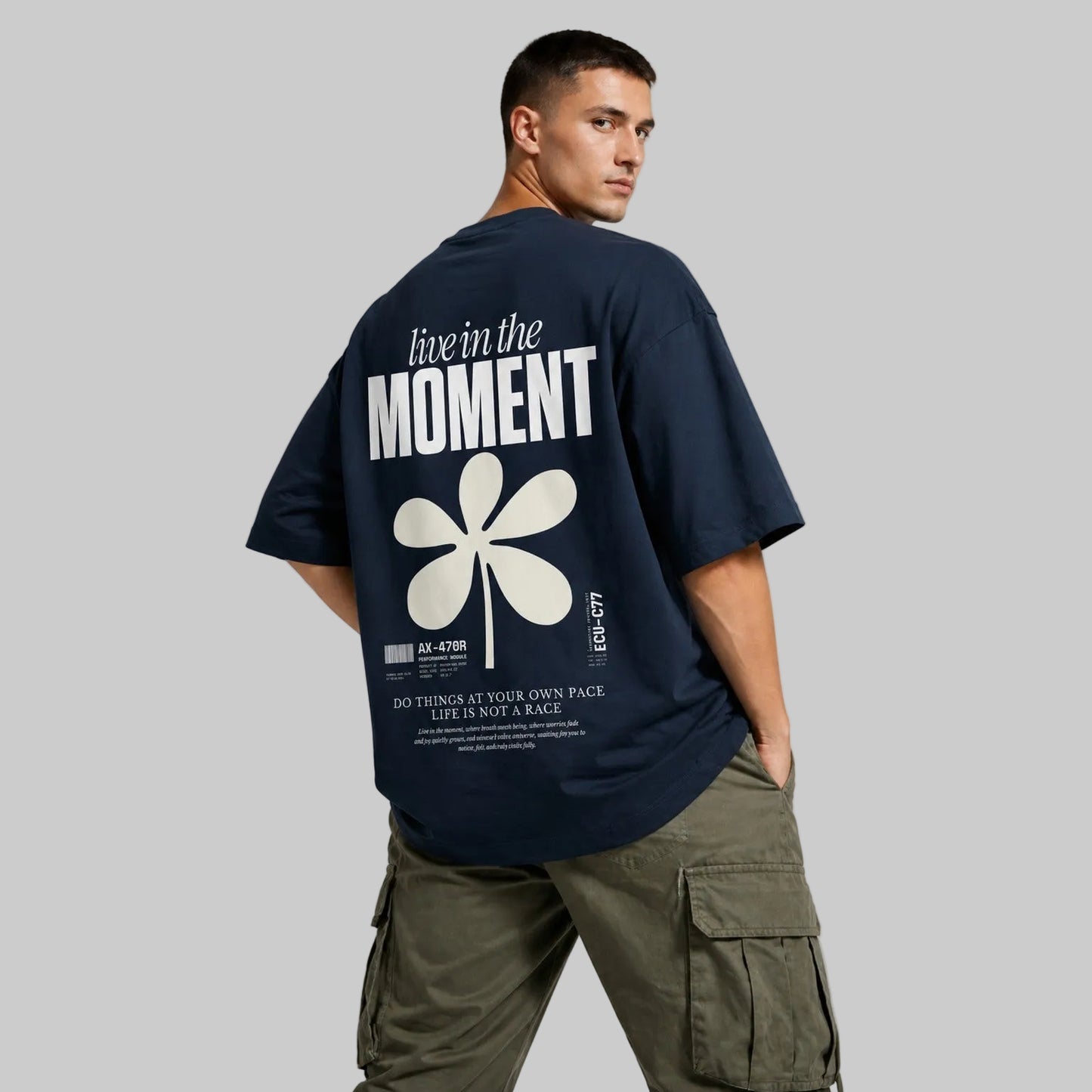 Man wearing a navy blue t-shirt with a white flower design and text on the back, standing against a gray background.