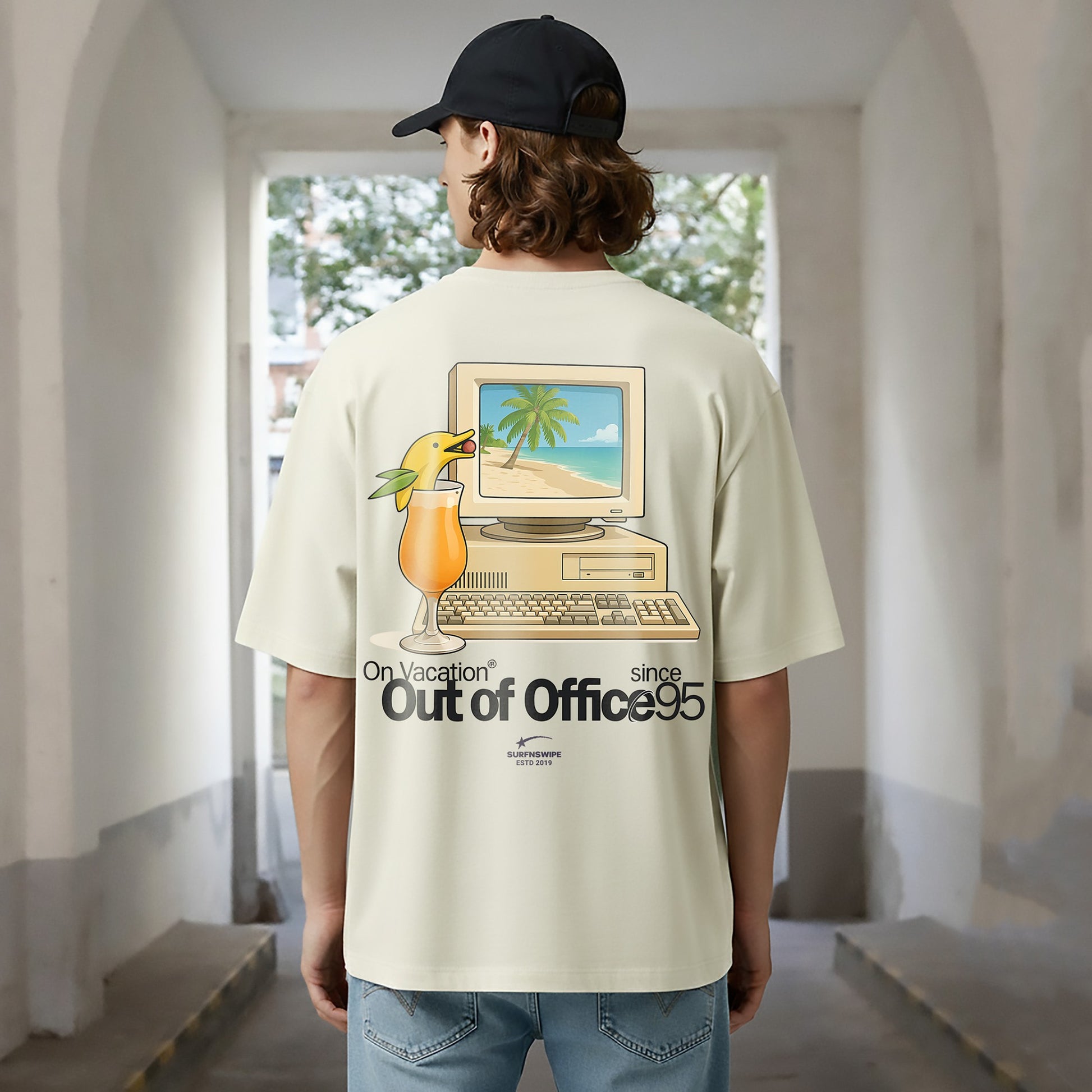 Person wearing a t-shirt with a graphic design of a computer and a drink, standing in an indoor setting.