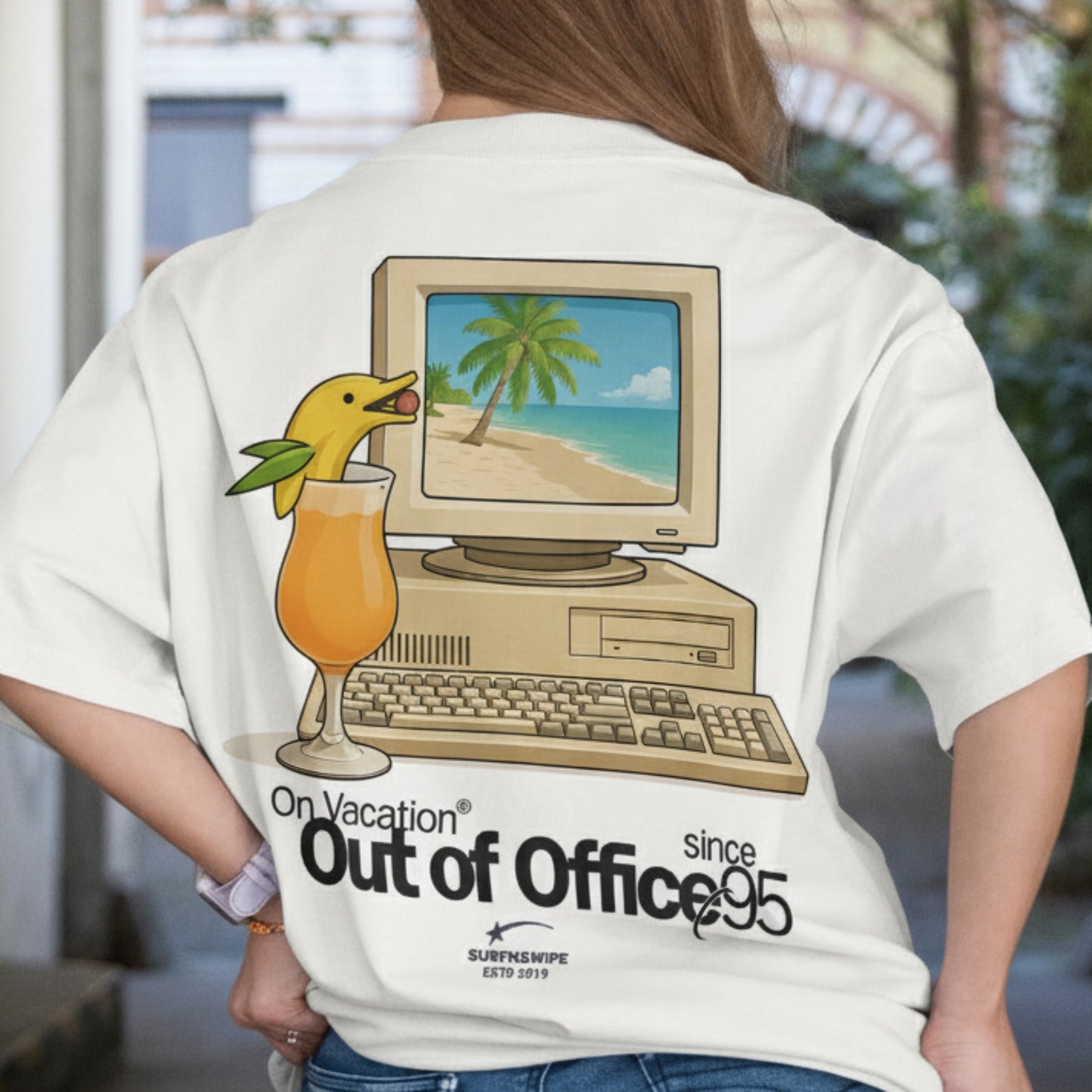 Person wearing a t-shirt with a vintage computer and beach scene design.