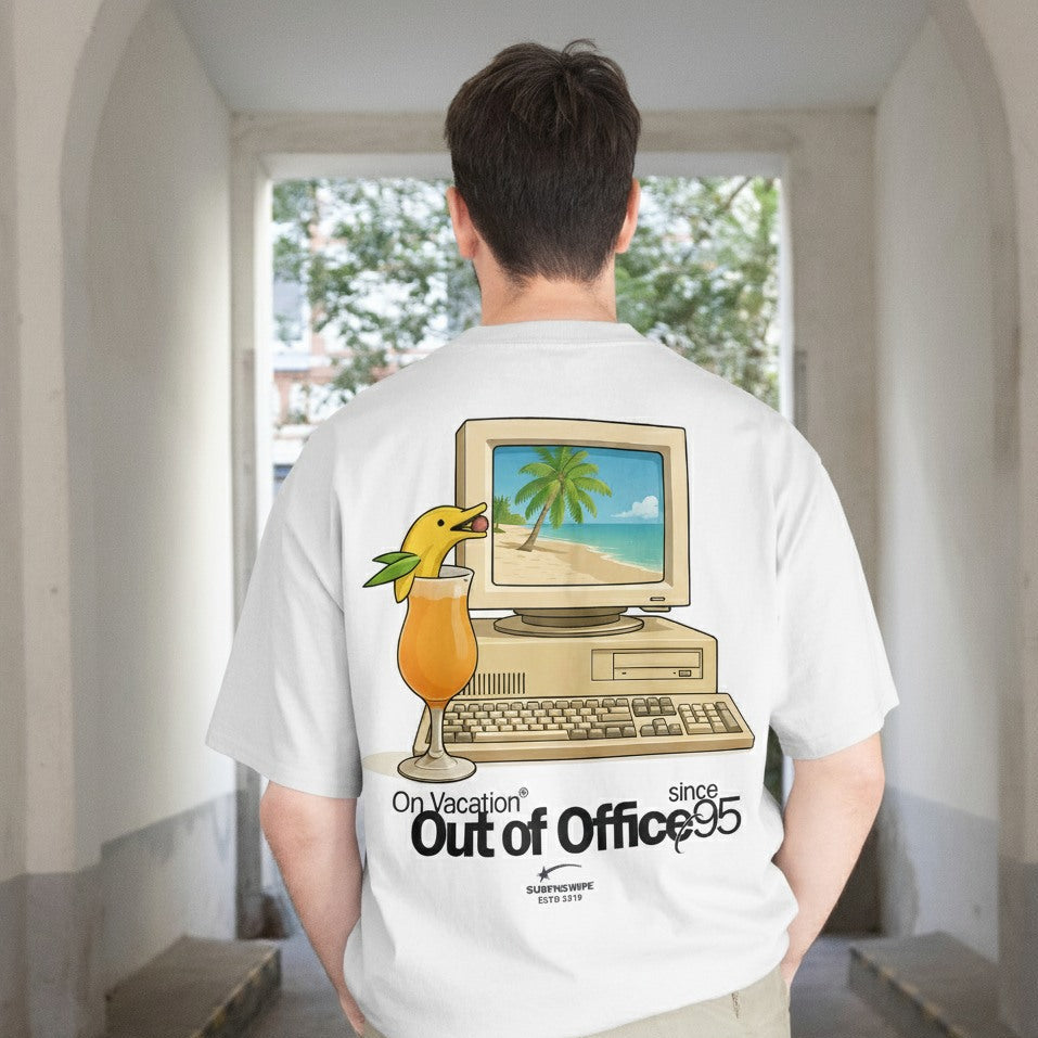 Person wearing a white t-shirt with a graphic design of a computer and beach scene, standing in a room with a window.