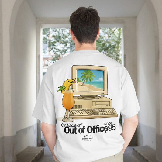 Person wearing a white t-shirt with a graphic design of a computer and beach scene, standing in a room with a window.