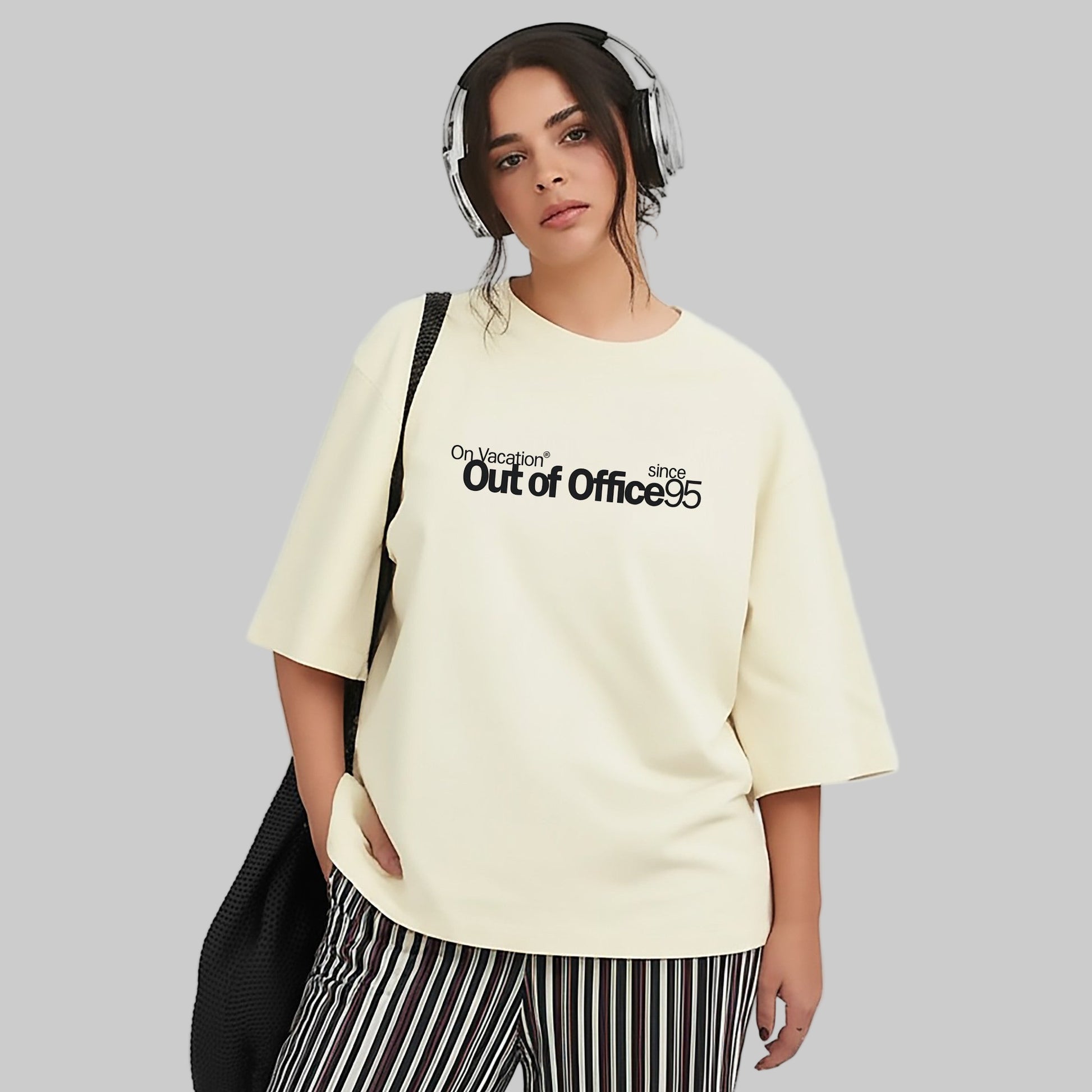 Person wearing a cream-colored t-shirt with text and striped pants on a white background