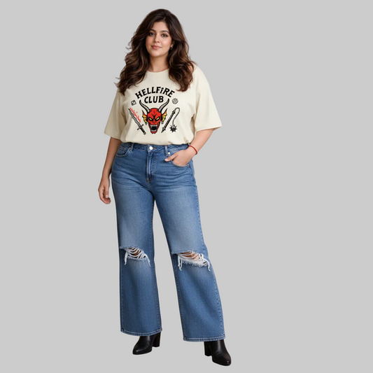 Woman wearing a graphic t-shirt and blue jeans against a neutral background