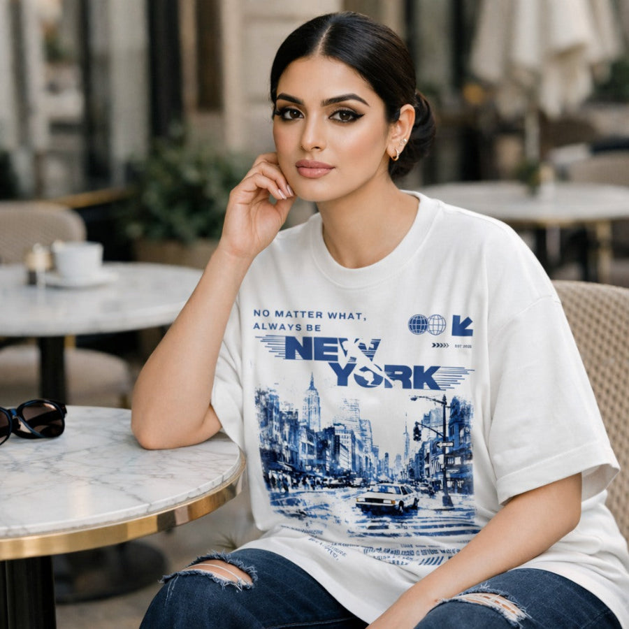 Woman wearing a white t-shirt with New York design sitting in a cafe.
