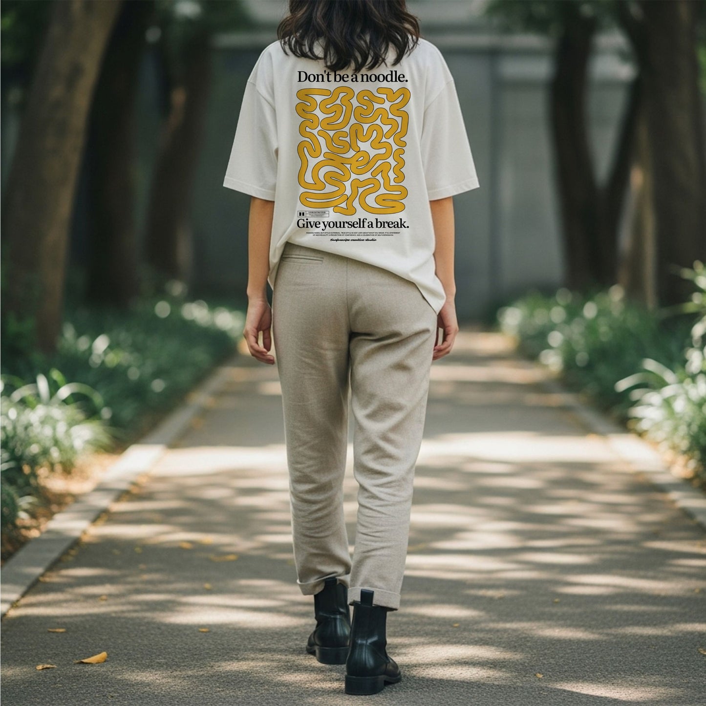 Person walking on a path wearing a white t-shirt with yellow text and graphics.