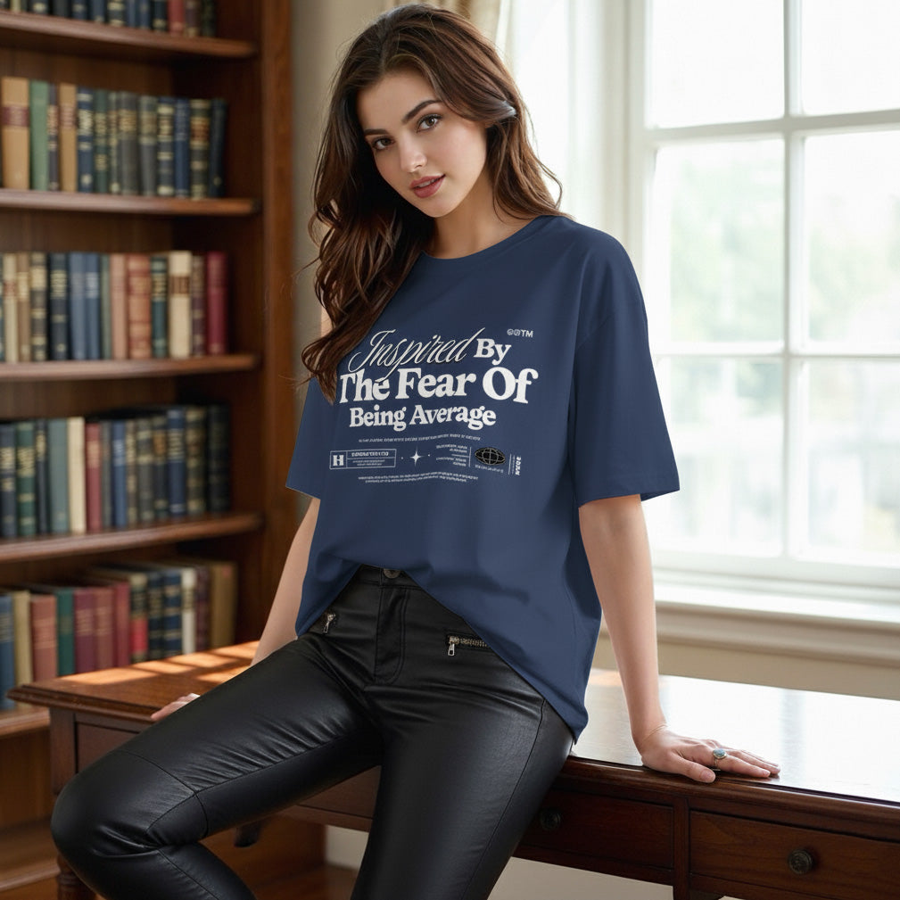 Woman wearing a blue t-shirt with text, sitting in a room with bookshelves and a window.