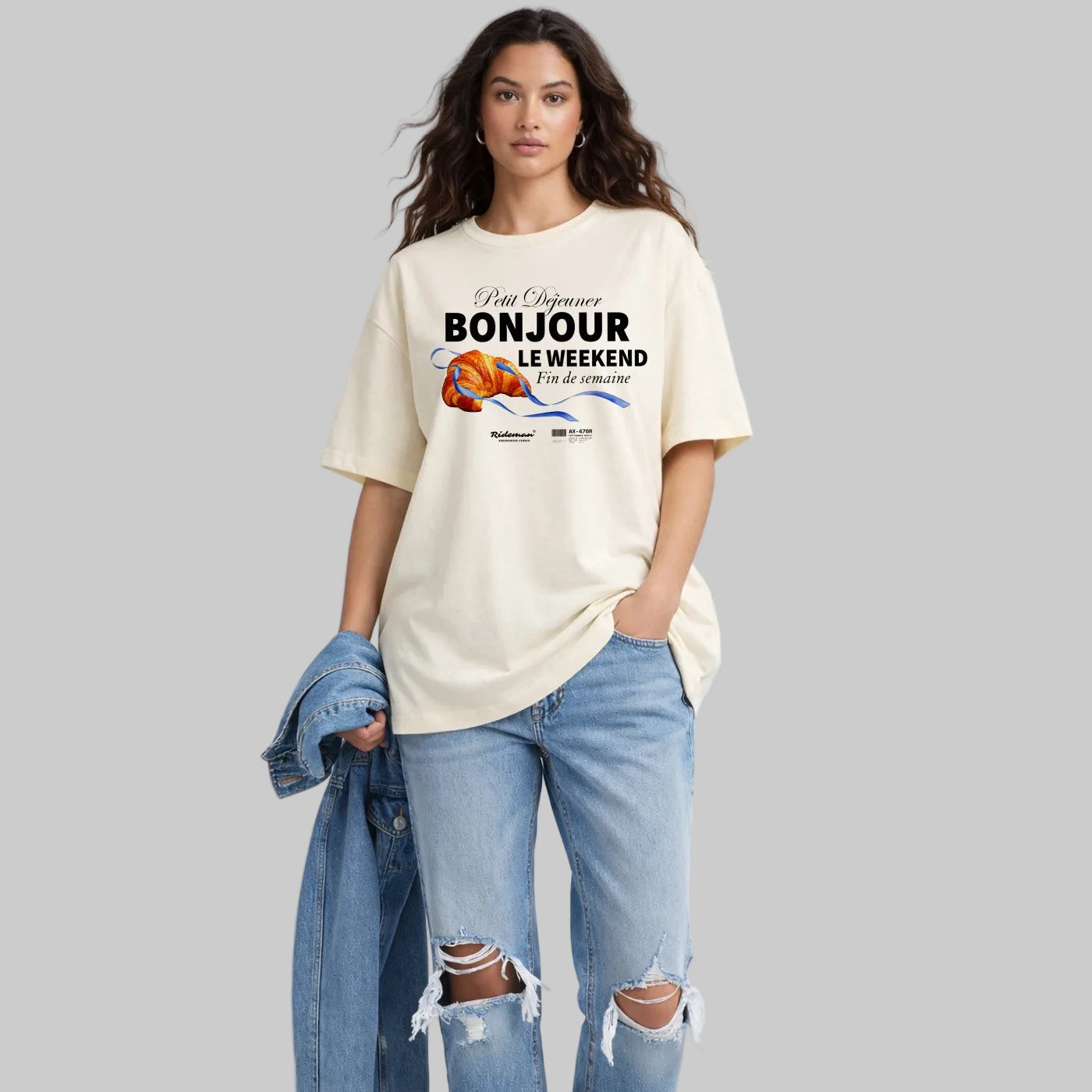 Woman wearing a cream t-shirt with text and graphics, standing against a light gray background