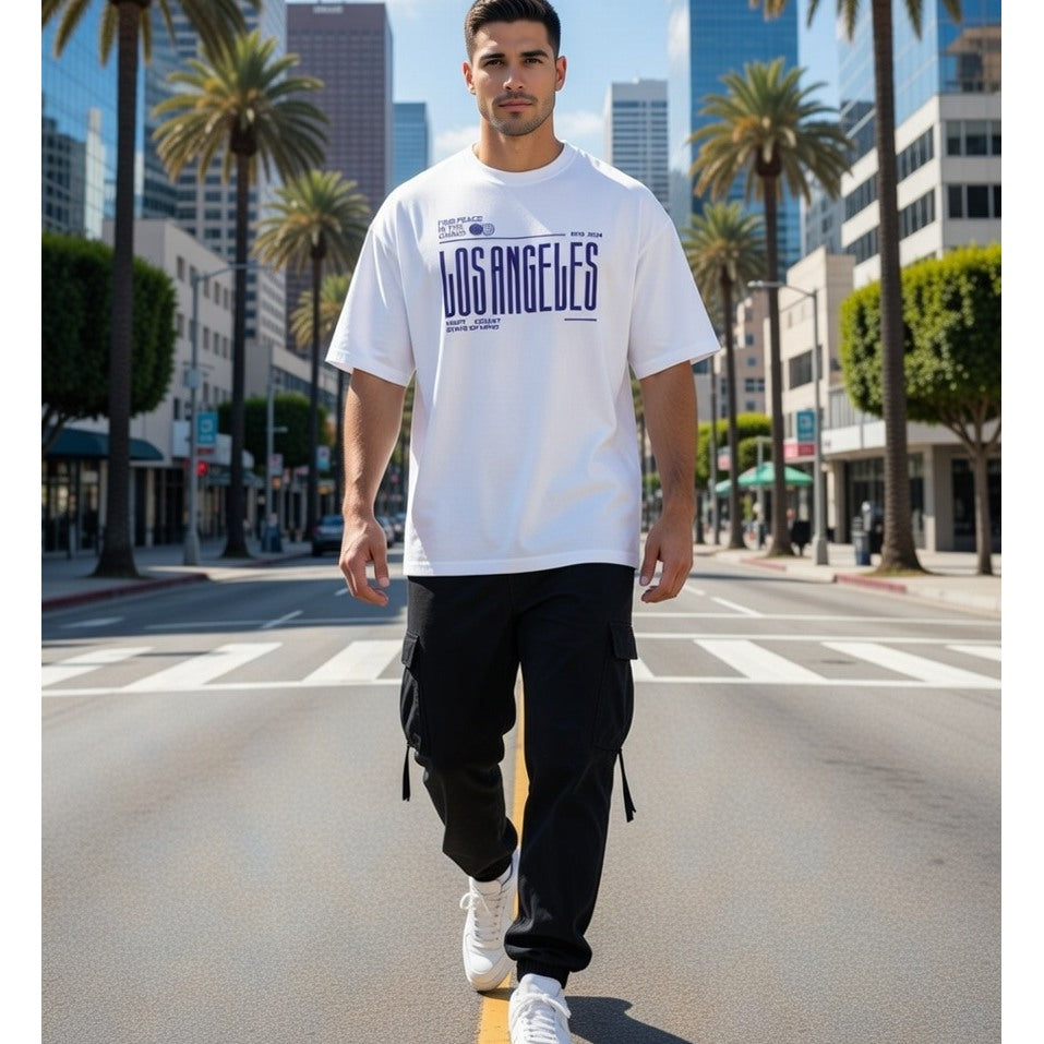 Man walking on a city street wearing a white t-shirt with 'Los Angeles' text.