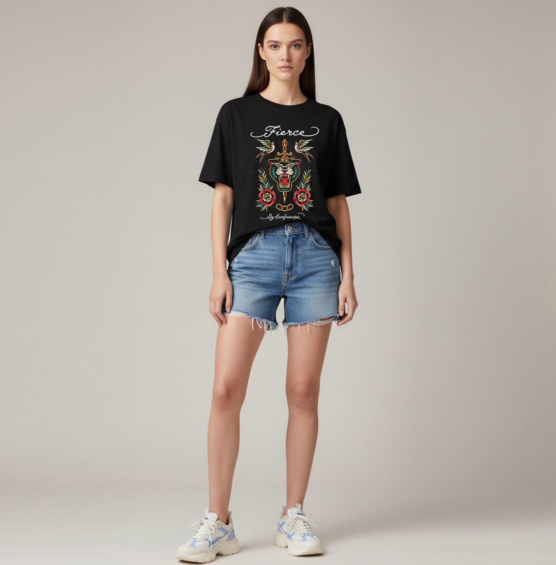 Woman wearing a black t-shirt with colorful graphics and text, paired with denim shorts on a plain background