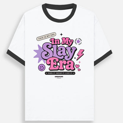 White ringer t-shirt with black collar and sleeve trim, featuring a colorful graphic on the front that reads 'In My Slay Era' in pink and purple lettering with stars and lightning bolts.