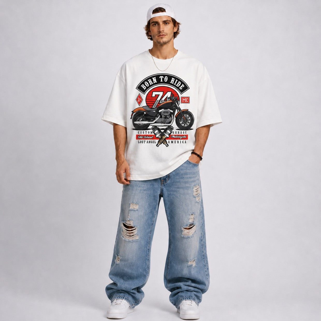 Man wearing a white t-shirt with a motorcycle graphic and text, paired with ripped jeans on a plain background