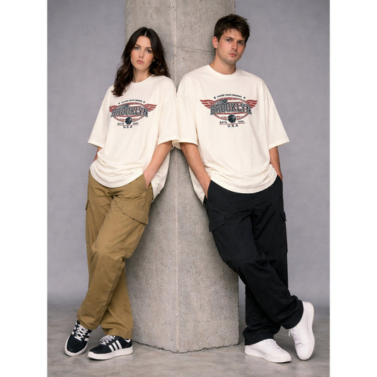 Two people wearing matching white t-shirts leaning against a concrete pillar.