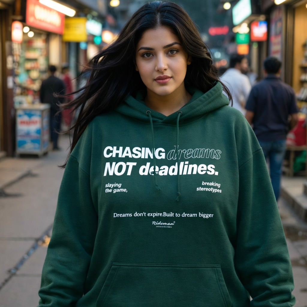 Woman wearing a green hoodie with motivational text in an urban setting