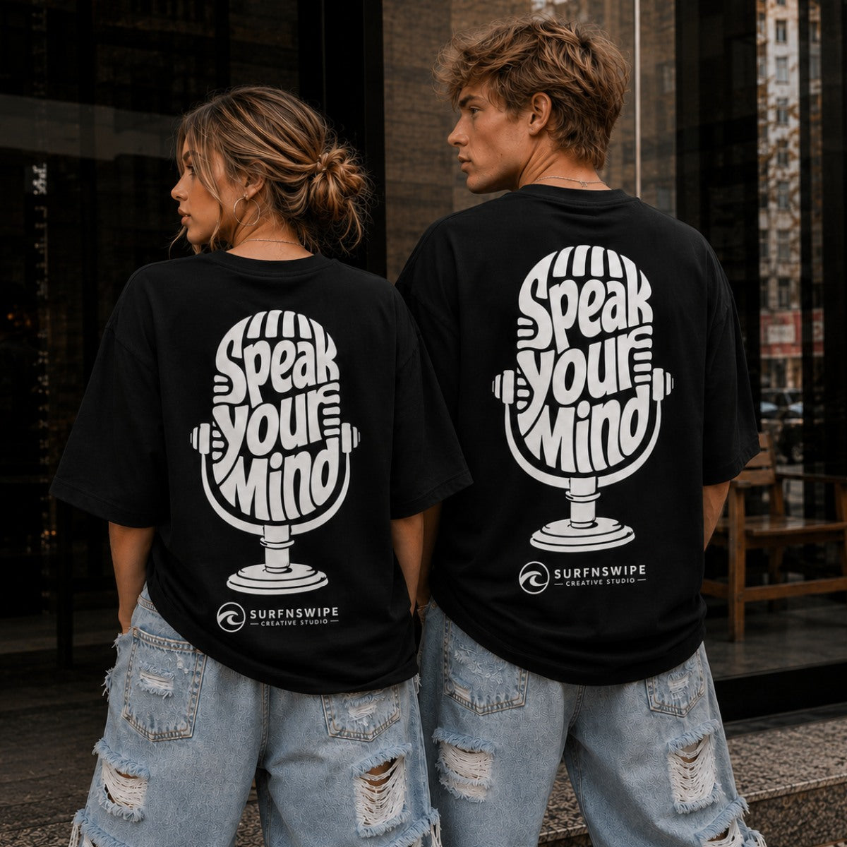Two people wearing black t-shirts with Speak Your Mind oversized graphic tee back print — vintage mic design on jet black heavyweight cotton