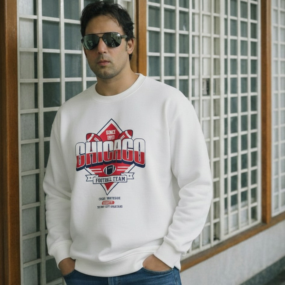 Man wearing a white sweatshirt with 'Chicago Football Team' design in front of a grid-patterned wall.