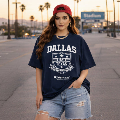 Woman wearing a navy blue t-shirt with 'Dallas, USA, Texas' text and graphics, standing in an outdoor setting.