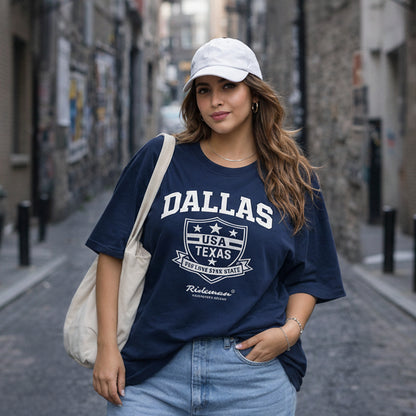 Woman wearing a navy blue t-shirt with 'Dallas, USA, Texas' text and graphics, standing on a street.