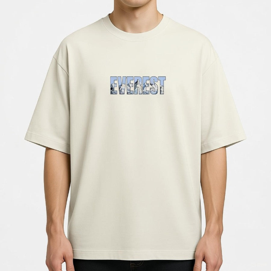 Beige t-shirt with 'Everest' text and mountain graphic worn by a person on a white background