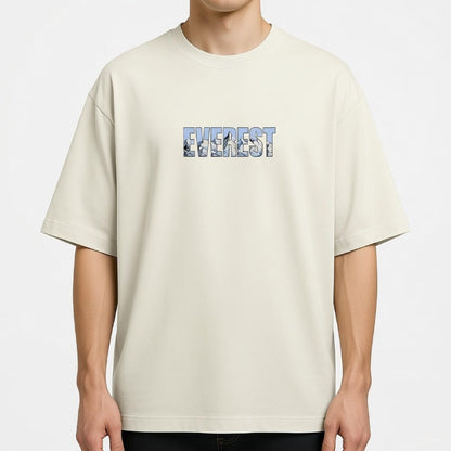 Beige t-shirt with 'Everest' text and mountain graphic worn by a person on a white background