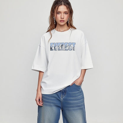 Woman wearing a white t-shirt with 'Everest' printed on it against a plain background