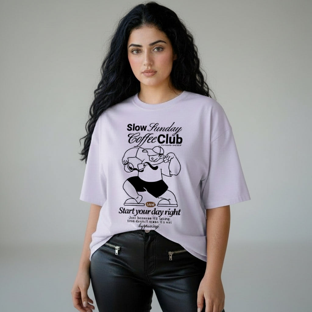 Woman wearing a light purple t-shirt with a graphic and text, standing against a neutral background.