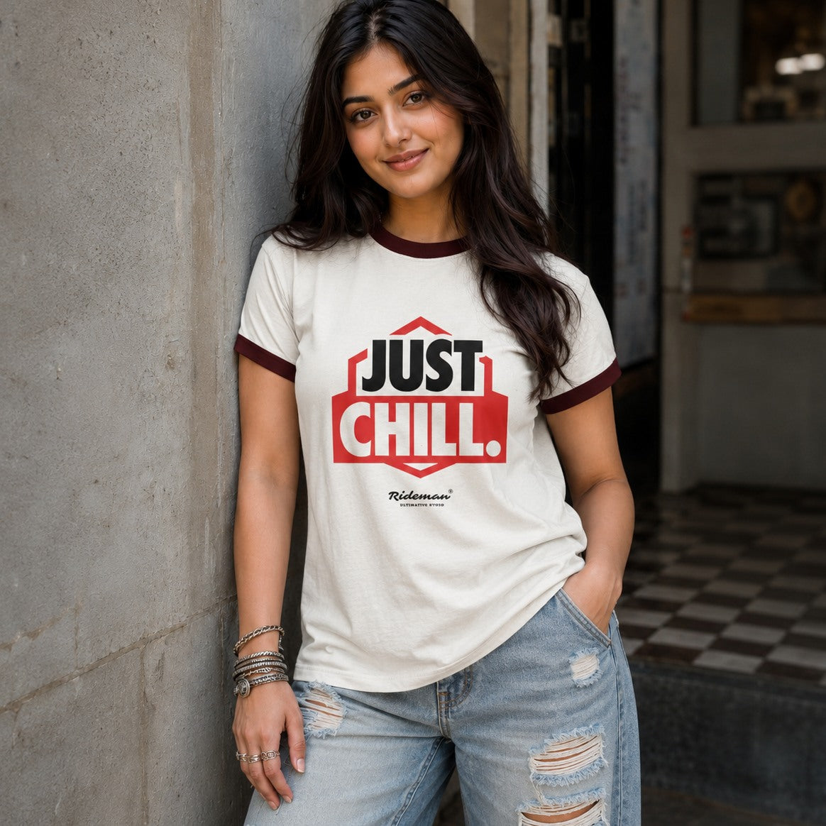 Woman wearing a 'Just Chill' t-shirt leaning against a wall.