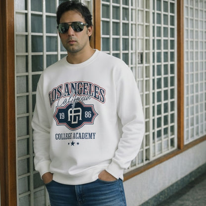 Man wearing a white sweatshirt with 'Los Angeles College Academy' print, standing against a grid-patterned wall.