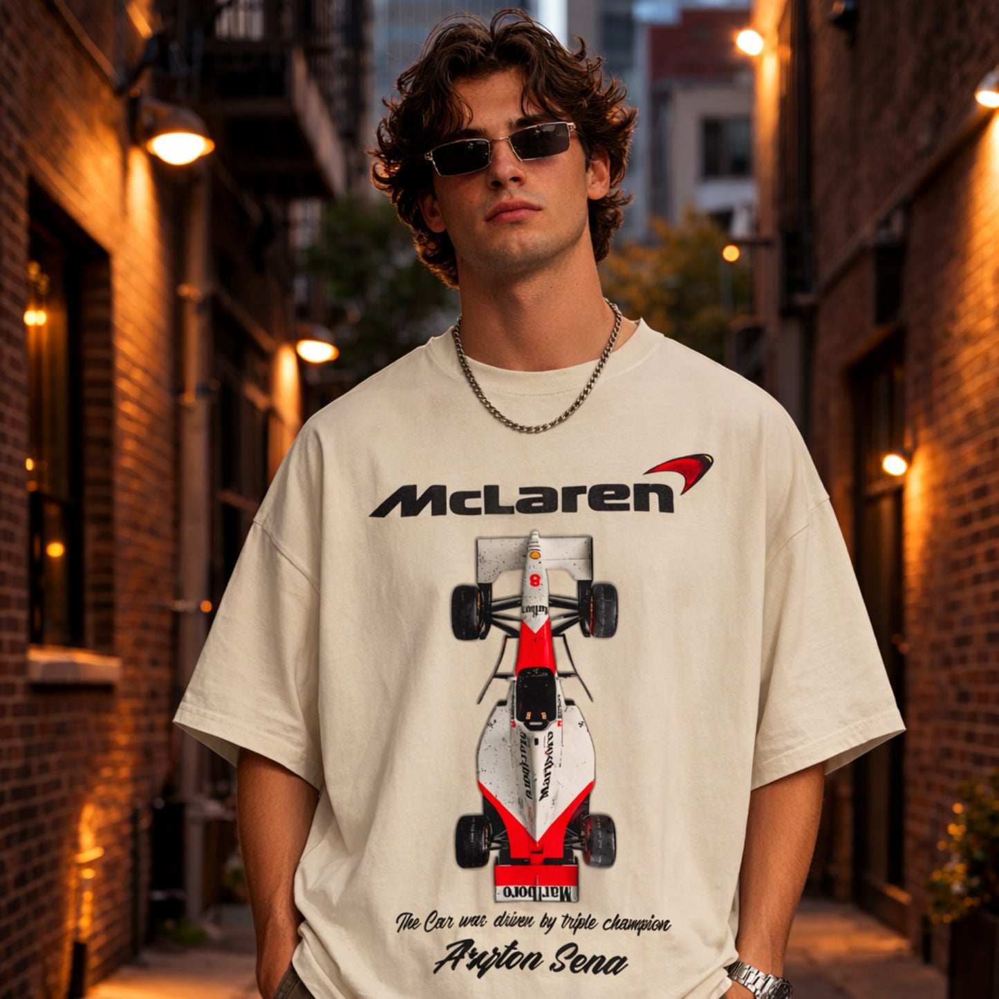 Person wearing a beige t-shirt with a McLaren logo and Formula 1 car design, standing in an urban alleyway.