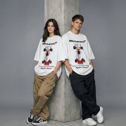 Two people wearing McLaren t-shirts with a race car graphic against a gray background