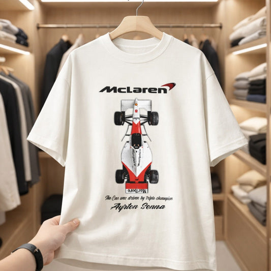 White t-shirt with McLaren Formula 1 car design held in a clothing store.