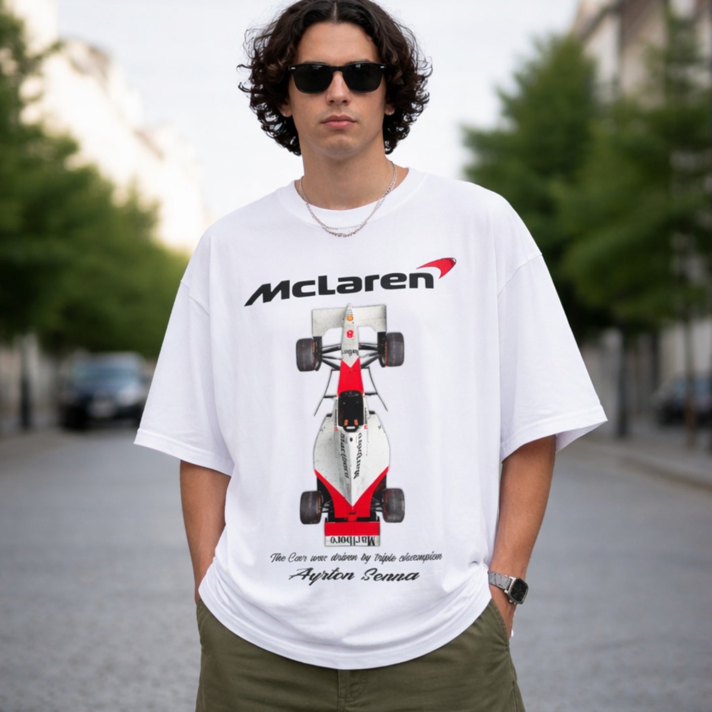 Person wearing a white McLaren t-shirt with a racing car design outdoors.