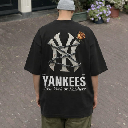 Person wearing a black t-shirt with 'Yankees' logo and text, standing on a paved area.