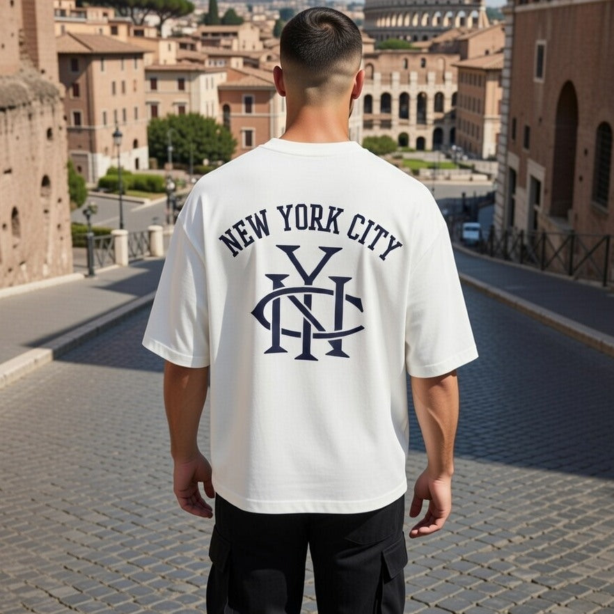 Person wearing a white t-shirt with 'New York City' text and logo in an urban setting.