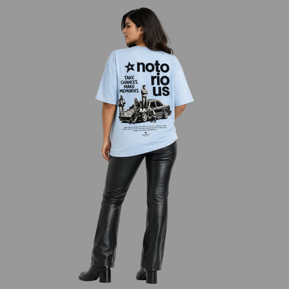 Person wearing a light blue t-shirt with a graphic design and text, standing against a white background