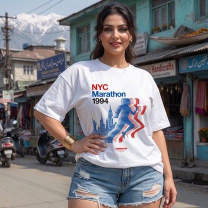 Woman wearing a NYC Marathon 1994 t-shirt on a street with shops and mountains in the background