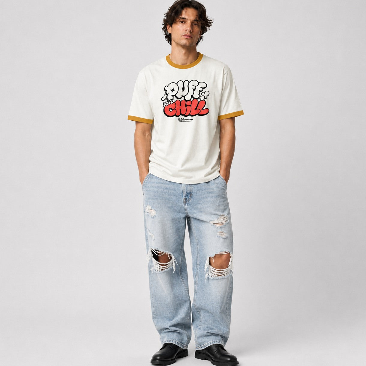 Person wearing a white t-shirt with colorful text and ripped jeans on a plain background