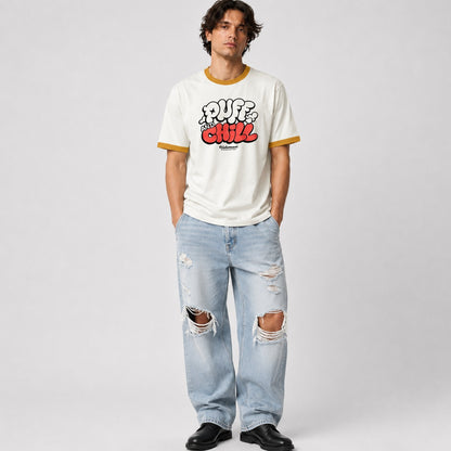 Person wearing a white t-shirt with colorful text and ripped jeans on a plain background