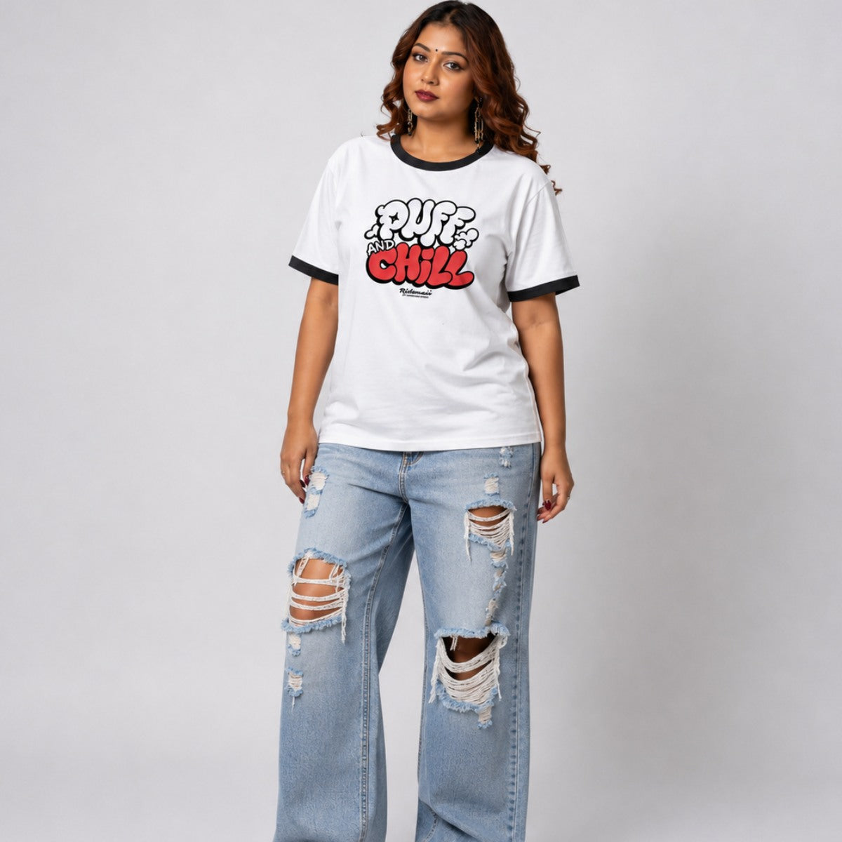 Woman wearing a white t-shirt with text and ripped jeans on a plain background