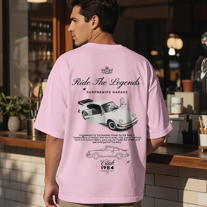 Person wearing a pink t-shirt with car graphics and text in an indoor setting