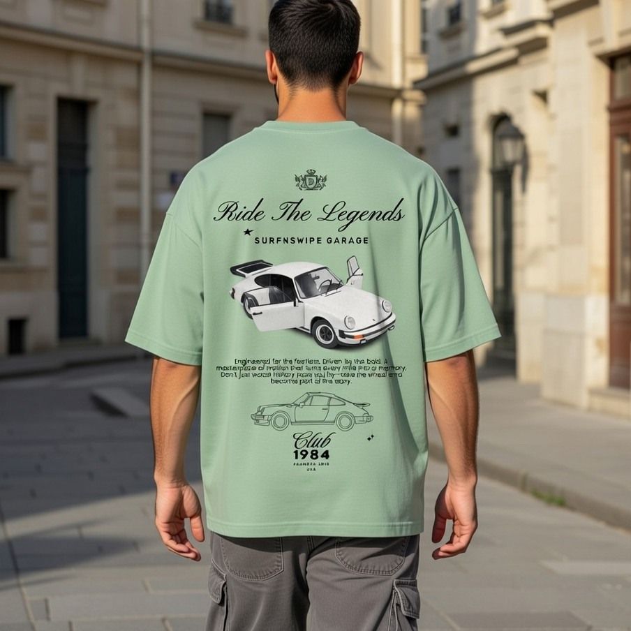 Person wearing a light green t-shirt with car graphics and text in an urban setting