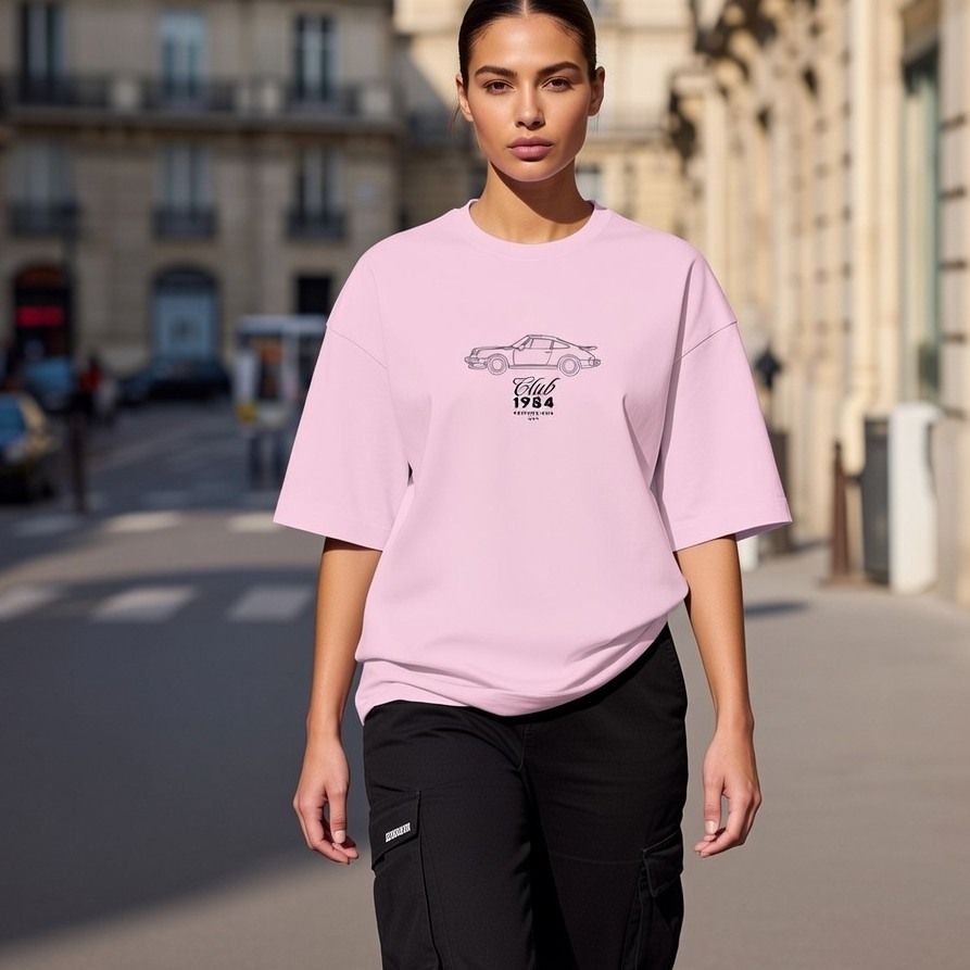Woman wearing a pink oversized t-shirt with a graphic design on a city street.