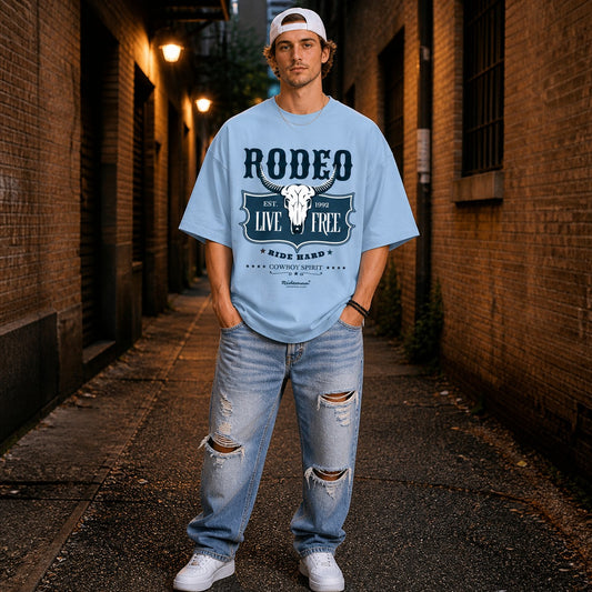 Man wearing a light blue t-shirt with 'Rodeo Live Free' design in an alleyway.