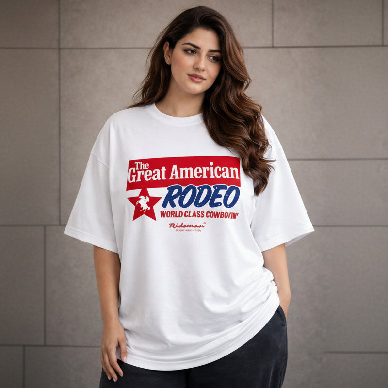 Woman wearing a white t-shirt with 'The Great American Rodeo' logo against a gray wall.