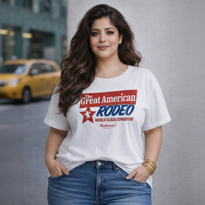 Woman wearing a white t-shirt with 'The Great American Rodeo' design, standing on a street.